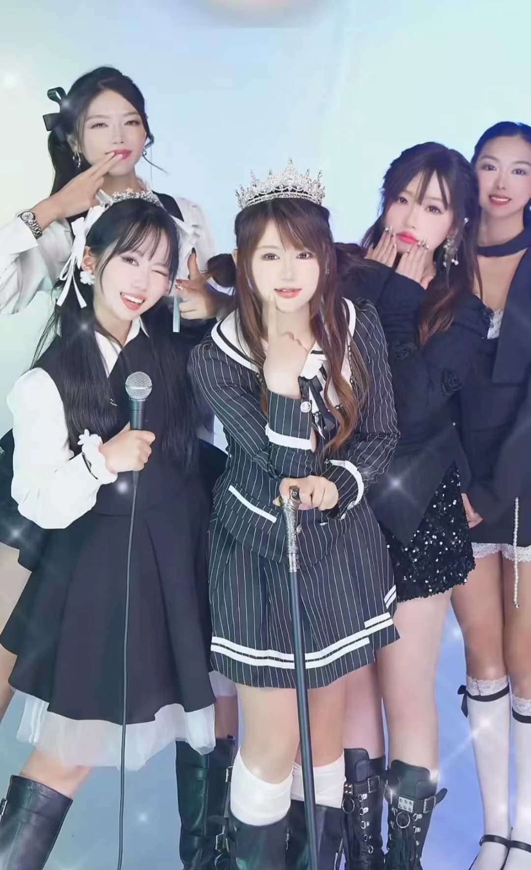 Stream styling group photo: five streamers in black-and-white uniform looks, holding a microphone and a sceptre on the studio floor
